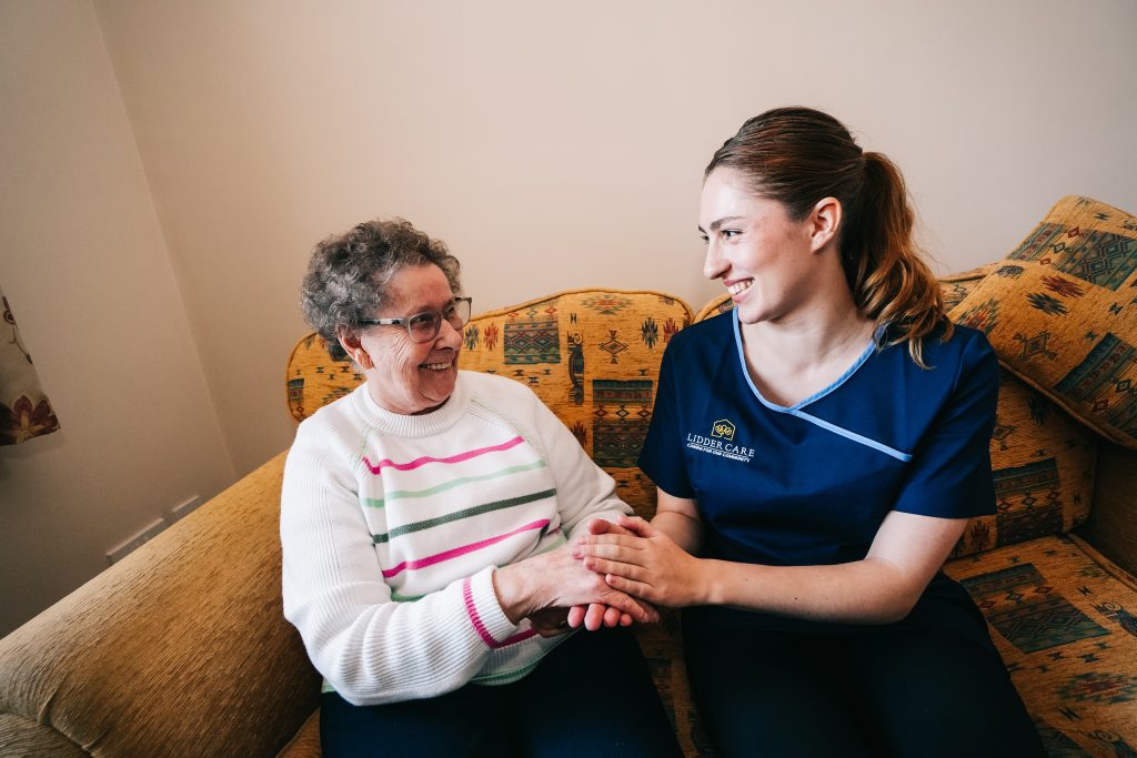 Carer sits smiling with home care client.